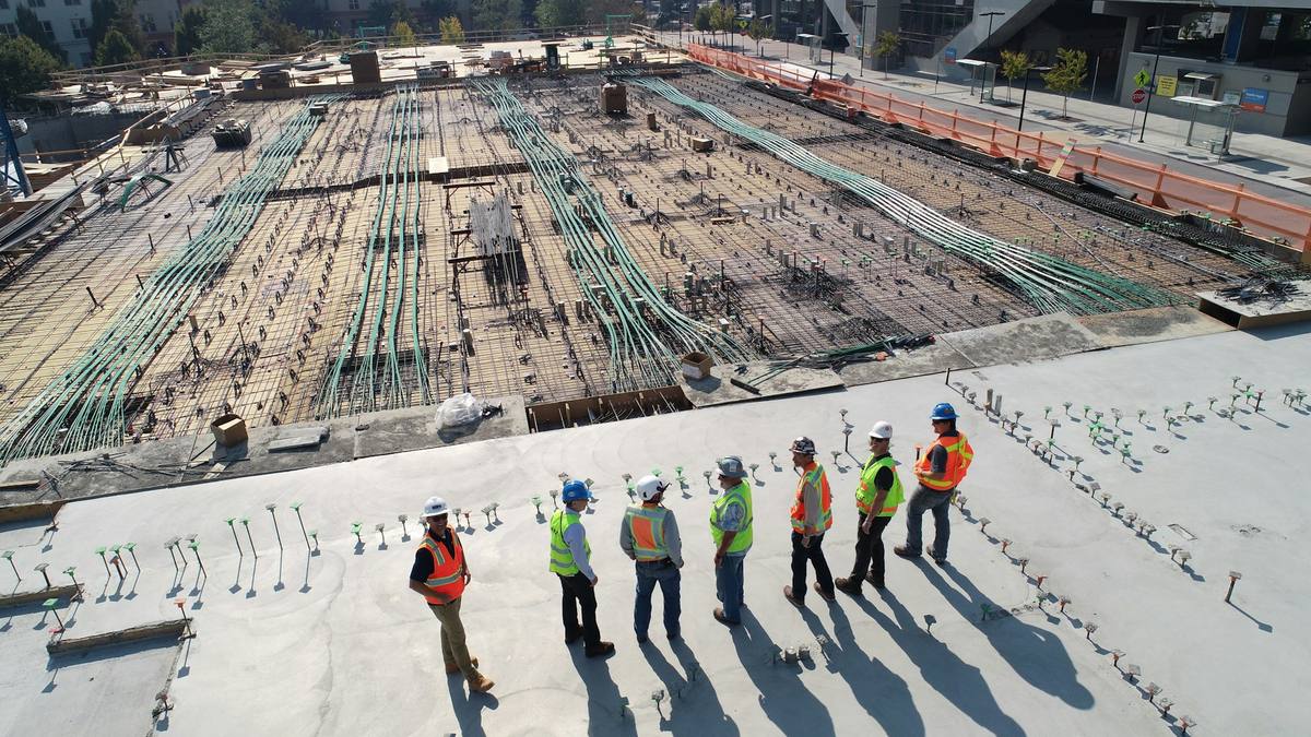 Equipo de operarios de construcción con casco y chaleco reflectante sobre la estructura de una obra
