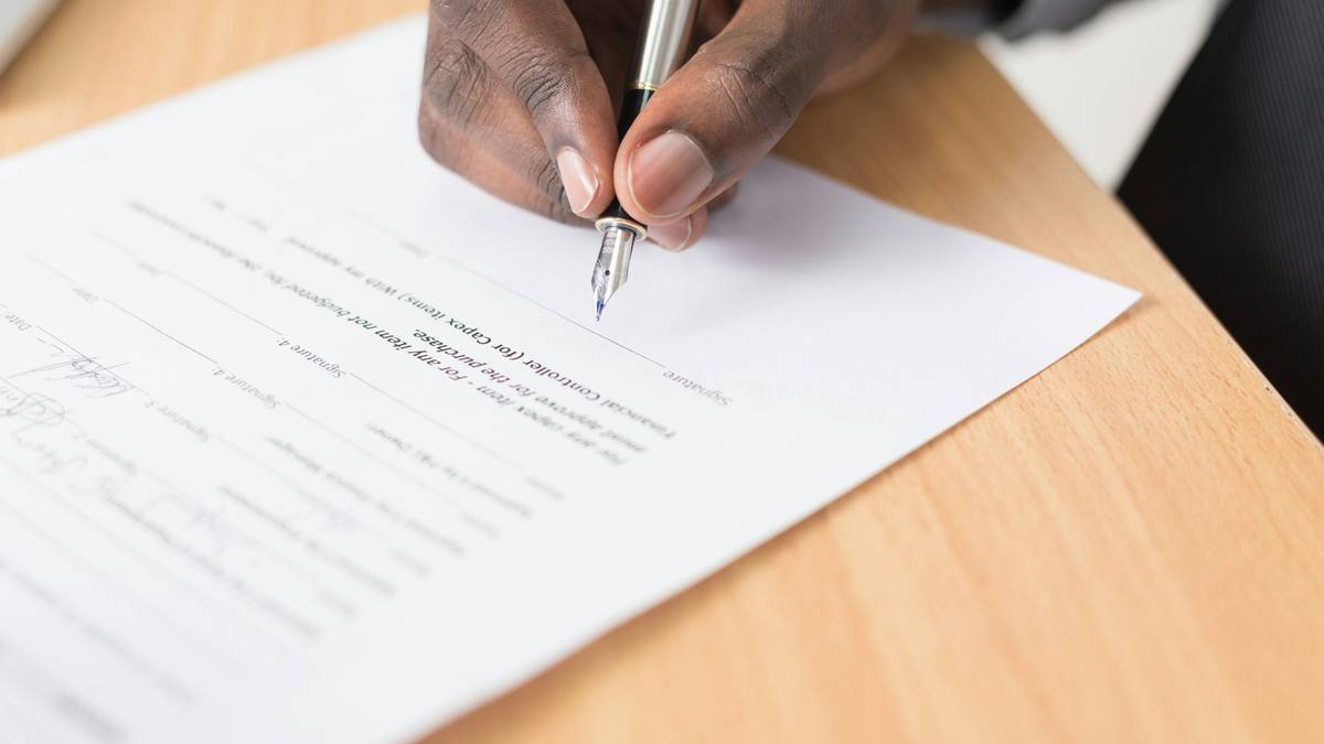 Firma de un contrato de trabajo con pluma estilográfica sobre mesa de madera